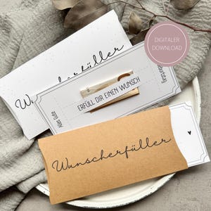 Pode incluir: Uma coleção de porta-cartões de presente em vários designs. Um é um envelope castanho com a palavra "Wunscherfüller" em escrita. Outro é um cartão branco com o texto "Erfüll dir einen Wunsch". A imagem também inclui um rótulo de download digital.