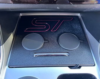 May include: A black car interior with a wireless charging pad featuring the red "ST" logo. The charging pad has two circular charging areas.