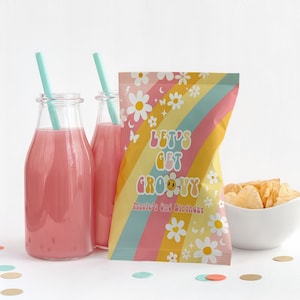 Puede incluir: Una bolsa de fiesta colorida con un diseño de arcoíris y margaritas. La bolsa dice "Let's Get Groovy" y "Happy 1st Birthday".