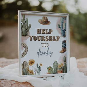 Könnte beinhalten: Ein weißes Schild mit braunem Holzrahmen, das ein Kaktus- und Cowboy-Stiefel-Design zeigt. Das Schild lautet "Help Yourself to drinks".