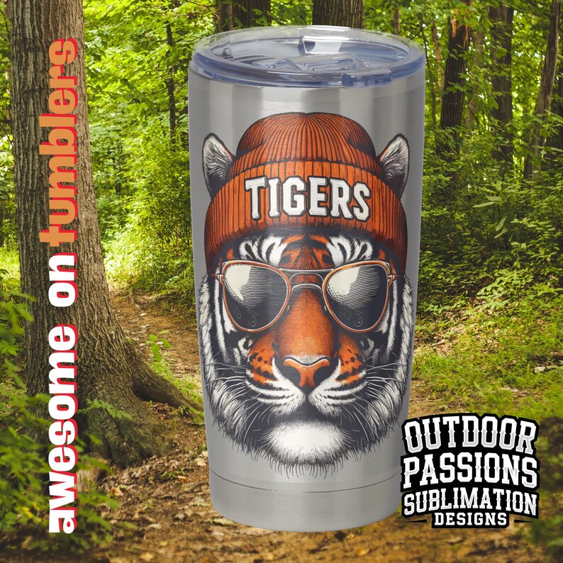 May include: A stainless steel tumbler featuring a tiger wearing a beanie hat and sunglasses. The beanie hat has the word "TIGERS" printed on it. The tumbler is a sublimation design.