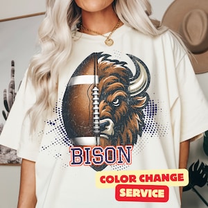 May include: White t-shirt with a graphic of a brown bison head with a football helmet on. The text "BISON" is below the graphic. The text "COLOR CHANGE SERVICE" is in a yellow and red rectangle at the bottom of the shirt.