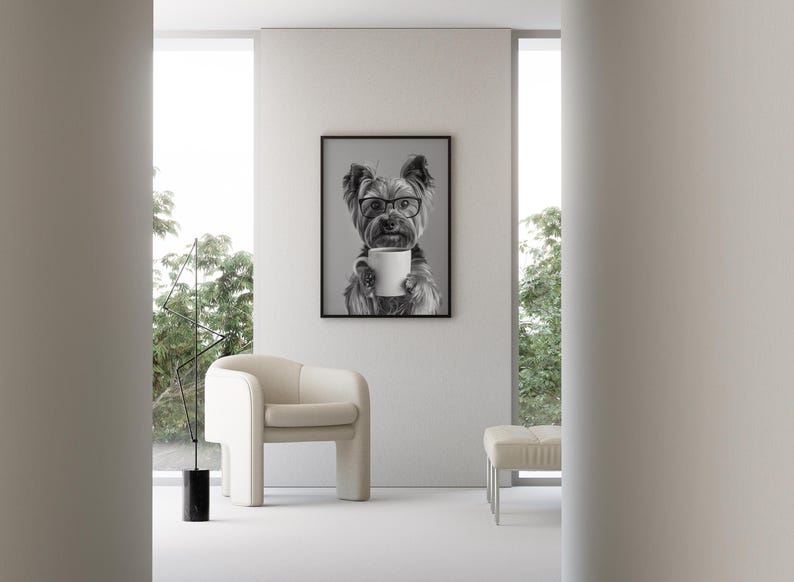 May include: A black and white photograph of a dog wearing glasses and holding a white coffee mug. The photo is framed and hanging on a white wall in a modern living room.