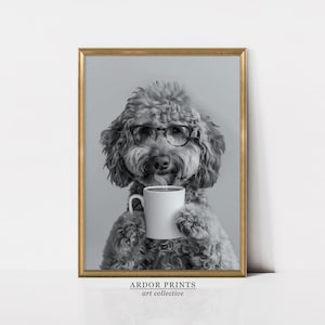 May include: A black and white photo of a dog wearing glasses and holding a white coffee mug. The dog is a poodle with a fluffy coat and a serious expression. The photo is framed in a gold frame.