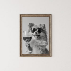 Peut inclure: Une photo en noir et blanc d'un chien portant des lunettes de soleil et tenant un verre de vin rouge. Le chien sourit et regarde la cam&eacute;ra.