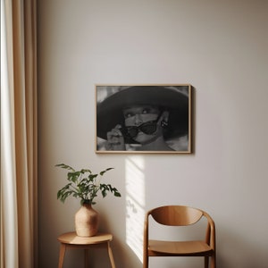 Pu&ograve; includere: Fotografia in bianco e nero di una donna con un cappello grande e occhiali da sole. La donna guarda a destra del fotogramma. La fotografia &egrave; incorniciata in una semplice cornice di legno.