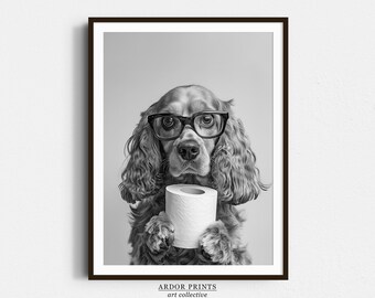 May include: A black and white photo of a dog wearing glasses and holding a roll of toilet paper. The dog is a cocker spaniel with long brown hair. The photo is printed on a white background.