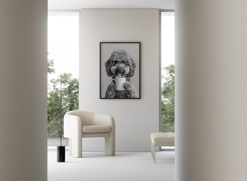 May include: A black and white photo of a dog wearing glasses and holding a white mug. The photo is framed in a black frame and hanging on a white wall.