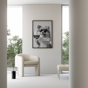 Peut inclure: Une photo en noir et blanc d'un chien portant des lunettes de soleil et tenant un verre de vin. La photo est encadr&eacute;e et accroch&eacute;e &agrave; un mur blanc dans un salon moderne.