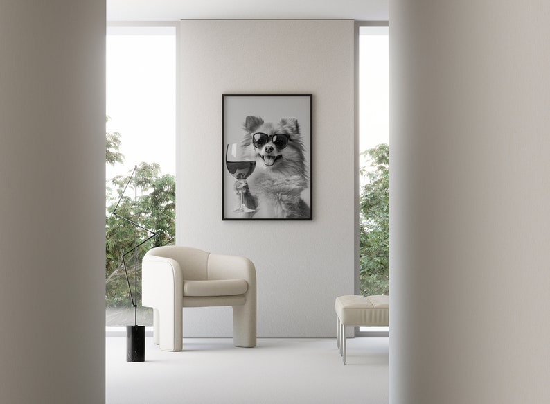 Peut inclure: Une photo en noir et blanc d'un chien portant des lunettes de soleil et tenant un verre de vin. La photo est encadr&eacute;e et accroch&eacute;e &agrave; un mur blanc dans un salon moderne.