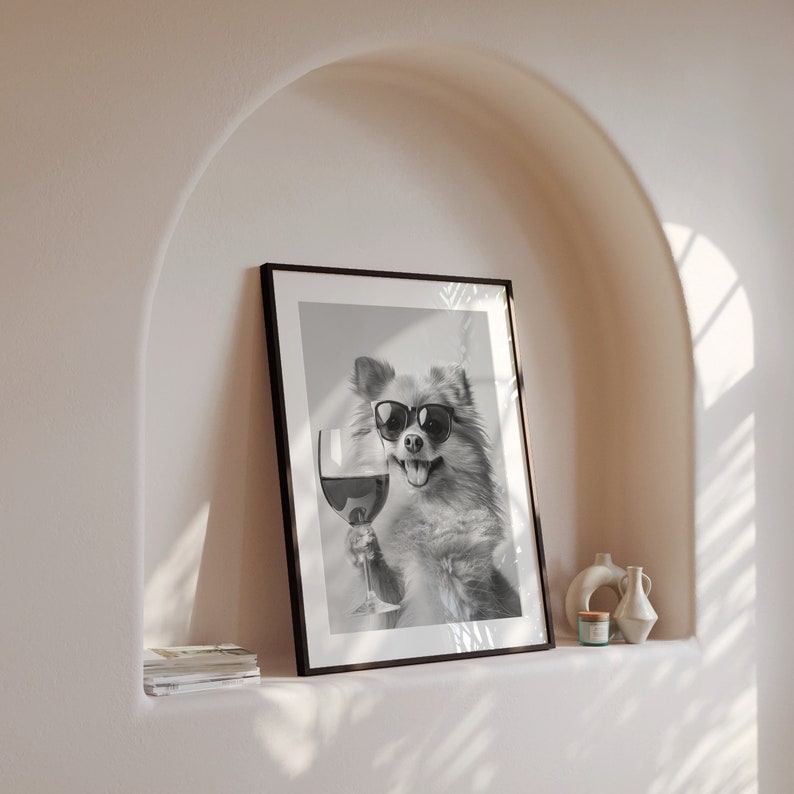Peut inclure: Photographie en noir et blanc d'un chien portant des lunettes de soleil et tenant un verre de vin. La photo est encadr&eacute;e dans un cadre noir et accroch&eacute;e &agrave; un mur.