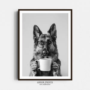 Könnte beinhalten: Schwarzweißfoto eines Deutschen Schäferhundes, der eine Brille trägt und eine weiße Kaffeetasse hält.