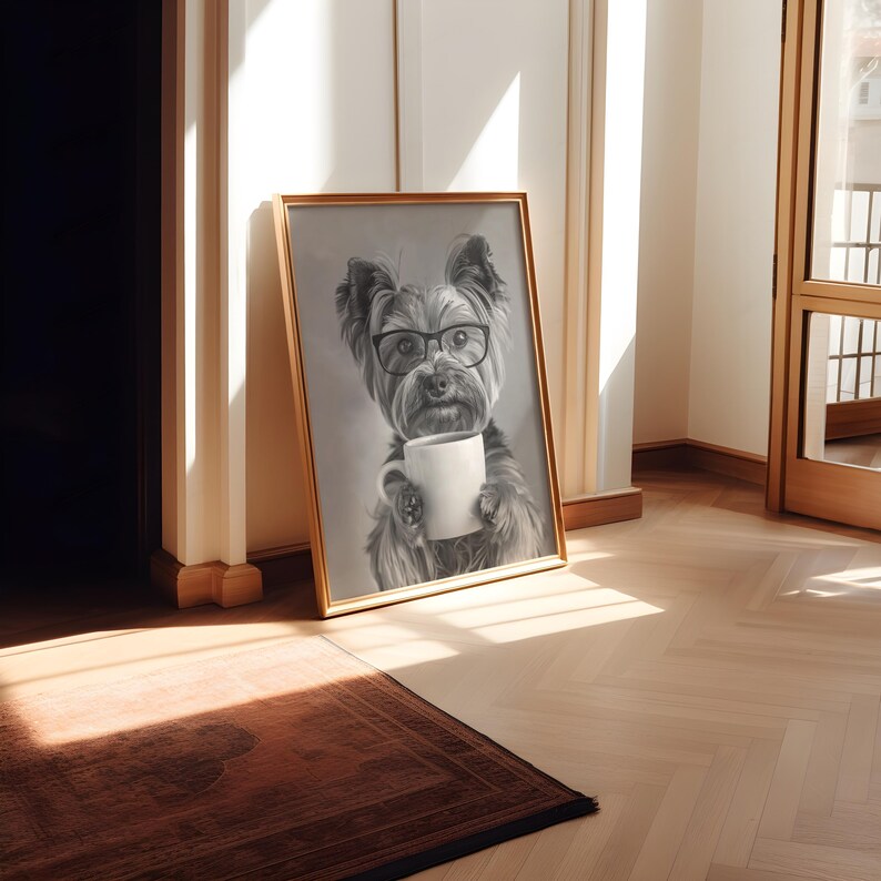 May include: A black and white illustration of a dog wearing glasses and holding a white coffee mug. The illustration is framed in a gold frame and is hanging on a white wall.