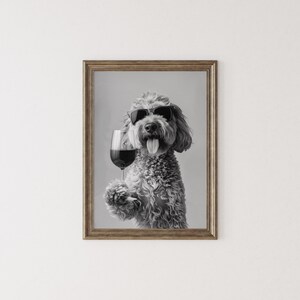 Pu&ograve; includere: Una foto in bianco e nero di un cane con occhiali da sole che tiene un bicchiere di vino rosso.