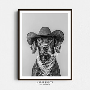 May include: A black and white photograph of a dog wearing a cowboy hat and a bandana, holding a cigar in its mouth.