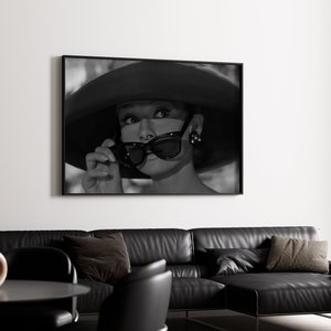 Pu&ograve; includere: Fotografia in bianco e nero di una donna con un cappello grande e occhiali da sole. La donna guarda a destra del fotogramma.