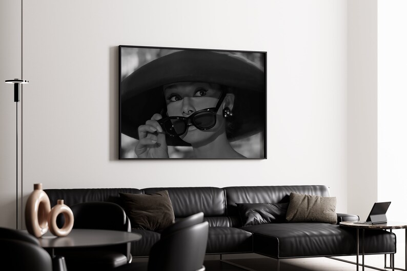 Pu&ograve; includere: Fotografia in bianco e nero di una donna con un cappello grande e occhiali da sole. La donna guarda a destra del fotogramma.