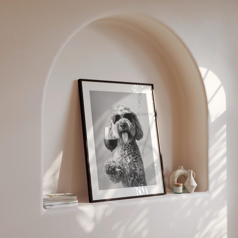 Pu&ograve; includere: Foto in bianco e nero di un cane con occhiali da sole che tiene un bicchiere di vino. La foto &egrave; incorniciata in una cornice nera e appesa a un muro.