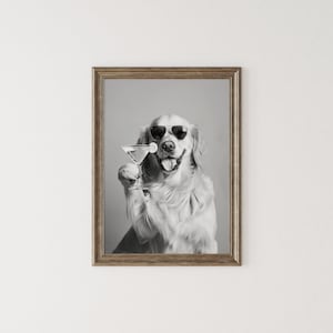 Op de afbeelding: Een zwart-witfoto van een golden retriever met een zonnebril die een martini-glas vasthoudt.
