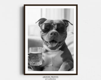 May include: A black and white photo of a dog wearing sunglasses and holding a glass of liquid. The dog is smiling and looking at the camera. The photo is framed in a black frame with the text "ARDOR PRINTS art collective" at the bottom.
