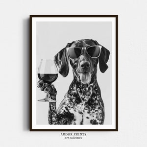 Può includere: Foto in bianco e nero di un cane che indossa occhiali da sole e tiene un bicchiere di vino rosso. Il cane guarda direttamente la fotocamera con un'espressione giocosa. Il testo "ARDOR PRINTS art collective" è in fondo all'immagine.
