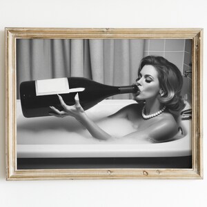Peut inclure: Une photographie en noir et blanc d'une femme dans une baignoire buvant une grande bouteille de champagne.