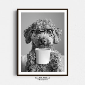 May include: A black and white photo of a dog wearing glasses and holding a cup of coffee. The dog is a poodle mix with curly fur. The photo is framed in a black frame.