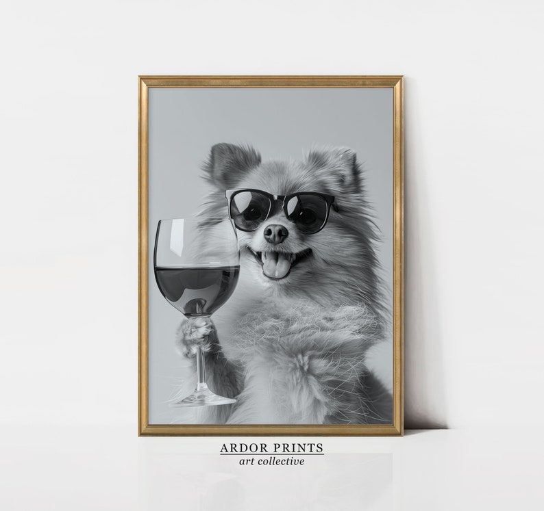 Peut inclure: Une photo en noir et blanc d'un chien portant des lunettes de soleil et tenant un verre de vin rouge. Le chien sourit et regarde la cam&eacute;ra. La photo est encadr&eacute;e dans un cadre dor&eacute;.