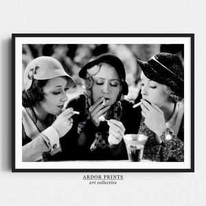 May include: Three women in vintage clothing and hats are sitting together, each holding a cigarette and looking at the camera. The photo is in black and white.