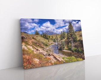 Puede incluir: Una pintura de paisaje que representa un río sinuoso que fluye a través de un valle rocoso. El río está rodeado de exuberantes árboles verdes y follaje, con una cordillera en la distancia. El cielo es azul brillante con nubes blancas y esponjosas.
