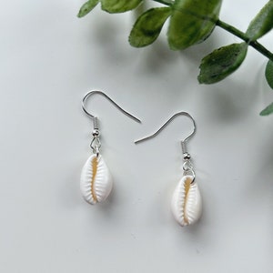 May include: A pair of silver earrings with white shell charms. The shells are smooth and have a natural, organic shape.