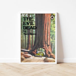 May include: Framed poster of "The Evil Dead" by Sam Raimi. The artwork shows a large tree with a car parked beneath it. The poster is in a white frame and is displayed on a wooden floor.
