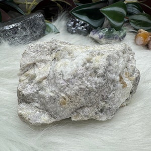 May include: A large, rough, gray and white rock with a white, fluffy background.