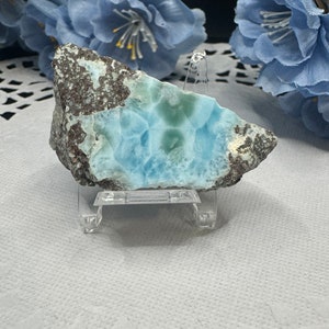 May include: A blue and green crystal with a gray matrix on a clear stand. The crystal has a unique, swirling pattern.