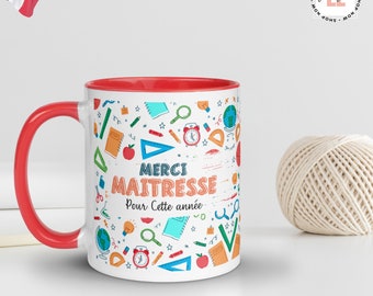 May include: White ceramic mug with a red rim. The mug features a colorful design of school supplies and the text "MERCI MAITRESSE Pour Cette année".