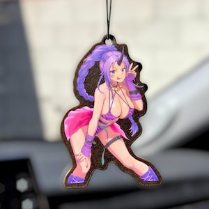 May include: A decorative air freshener featuring a purple-haired anime character with a horn, wearing a revealing purple and pink outfit. The character is making a peace sign. The air freshener is black with a string for hanging.