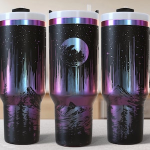 May include: Three stainless steel travel mugs with black handles and lids. The mugs have a black background with a colorful aurora borealis design and a silhouette of mountains and trees.