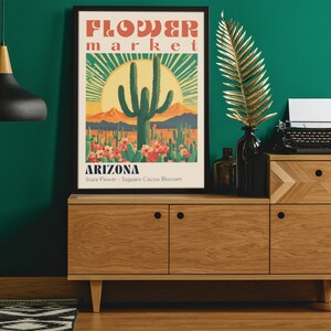 Op de afbeelding: Een poster in vintage stijl met een retro kleurenpalet dat een bloeiende Saguaro-cactus afbeeldt. De poster luidt "FLOWER market ARIZONA State Flower - Saguaro Cactus Blossom".