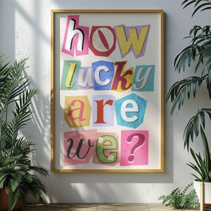 Op de afbeelding: Een kleurrijke poster met de tekst "how lucky are we?" in een uitknipstijl, waarbij elke letter een andere kleur en vorm heeft.