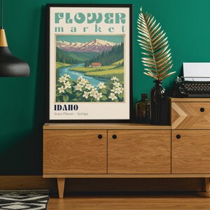 Może przedstawiać: Plakat w stylu vintage z tekstem "FLOWER market IDAHO State Flower - Syringa" i przedstawieniem rzeki płynącej przez dolinę z g&oacute;rami w tle.