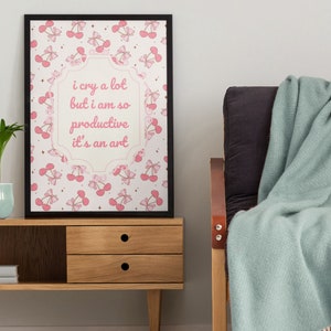 May include: A framed print with a pink and white cherry pattern and the text "i cry a lot but i am so productive it's an art".