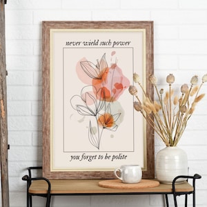 May include: A framed print featuring a floral design in shades of orange and pink. The print includes the text "never wield such power you forget to be polite".