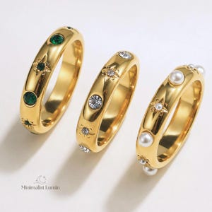 May include: Three gold-toned rings featuring star-shaped engravings and embedded accents. The first ring has green stones, the second has clear crystals, and the third has white pearls. The text Minimalist Lumin is printed in the bottom left corner.