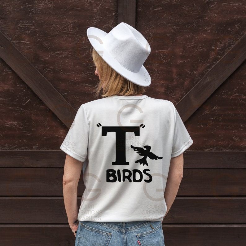 May include: White t-shirt with a black graphic of a bird flying next to a large black "T" and the text "BIRDS" underneath.