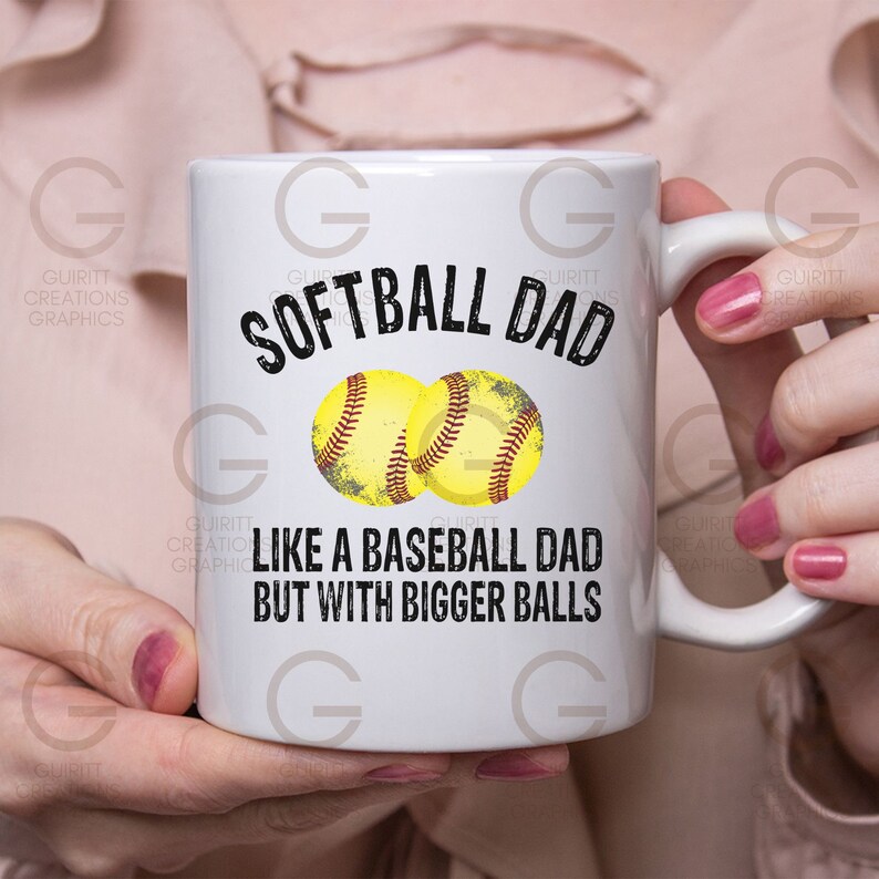 Może przedstawiać: Biały ceramiczny kubek do kawy z czarnym nadrukiem, na kt&oacute;rym widnieje napis "Softball Dad Like a Baseball Dad But With Bigger Balls". Nad tekstem znajdują się dwie ż&oacute;łte ilustracje piłek do softballa.