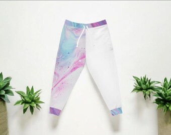 May include: White sweatpants with a drawstring waist and a colorful abstract design on the left leg. The design features swirls of blue, pink, and purple with a speckled effect. The cuffs are also patterned.