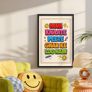 Könnte beinhalten: Ein gerahmter Kunstdruck mit dem Text "HUM KHAATE PEETE GHAR KE LOG HAIN" in farbenfrohen Buchstaben im Comic-Stil. Der Druck befindet sich in einem schwarzen Rahmen und hängt an einer weißen Wand über einem grünen Sofa.