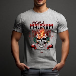 May include: Gray t-shirt with a skull graphic. The skull is wearing a crown with flames and surrounded by flowers. The text "NCALA MALEKUM" is above the skull. The text "ZAMBIA ARRIBA ZAMBIA ABAJO ZAMBIA A LOS CUATROS COSTADOS" is below the skull.