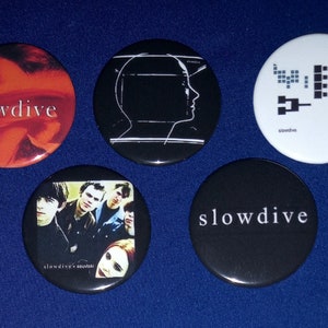 Puede incluir: Cinco botones redondos de la banda Slowdive en blanco y negro. Un botón presenta una imagen en blanco y negro de la cabeza de una persona. Otro botón presenta una imagen en blanco y negro de una banda. Un botón presenta la palabra "Slowdive" en texto blanco sobre fondo negro. Un botón presenta la palabra "Slowdive" en texto blanco sobre fondo rojo. Un botón presenta un diseño gráfico en blanco y negro con la palabra "Slowdive" en texto negro.