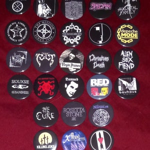 May include: A collection of 25 round black and white buttons with band names and logos. The buttons feature bands such as The Cure, Joy Division, Depeche Mode, Siouxsie and the Banshees, Killing Joke, and The Mission.